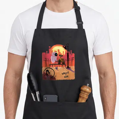 Tablier de cuisine noir avec Wall-E et Eve assis sur un banc devant un soleil orange et une ville en arrière-plan.