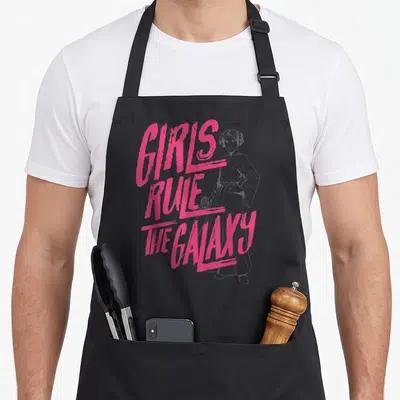 Tablier de cuisine noir avec illustration rose de Princess Leia et le texte Girls Rule The Galaxy imprimé en gros caractères stylisés.
