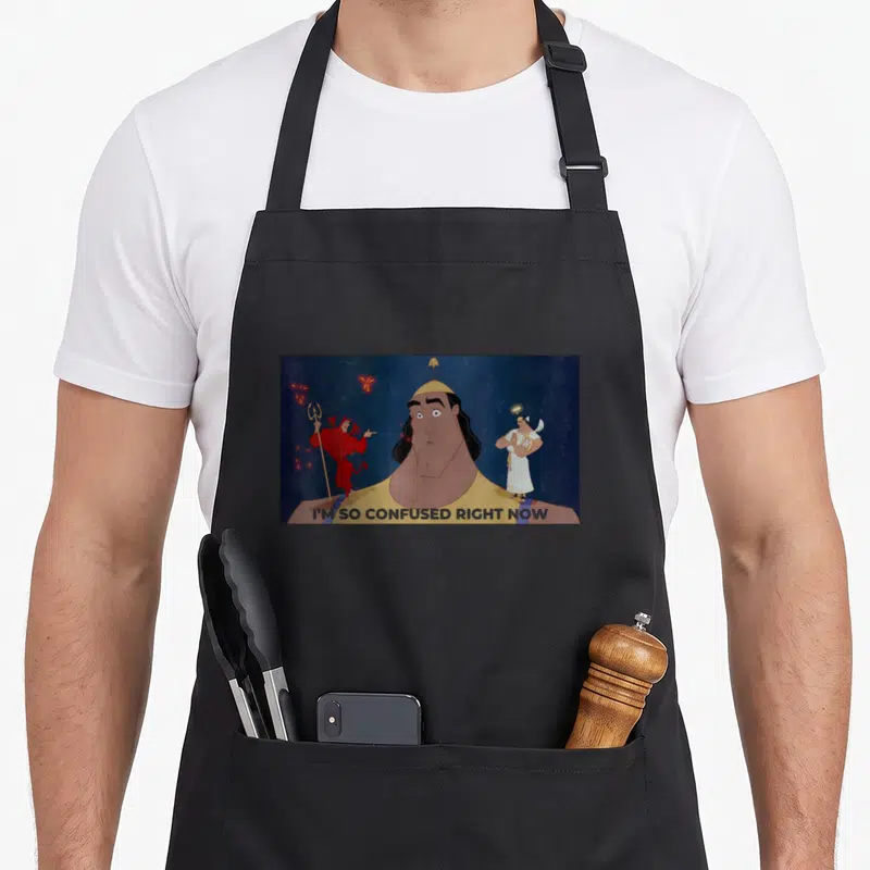 Tablier de cuisine noir avec Kronk confus, un diable rouge et un ange blanc sur fond bleu nuit.