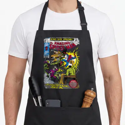 Tablier de cuisine noir avec une illustration colorée de Spider-Man combattant ses ennemis sur fond de bande dessinée américaine.