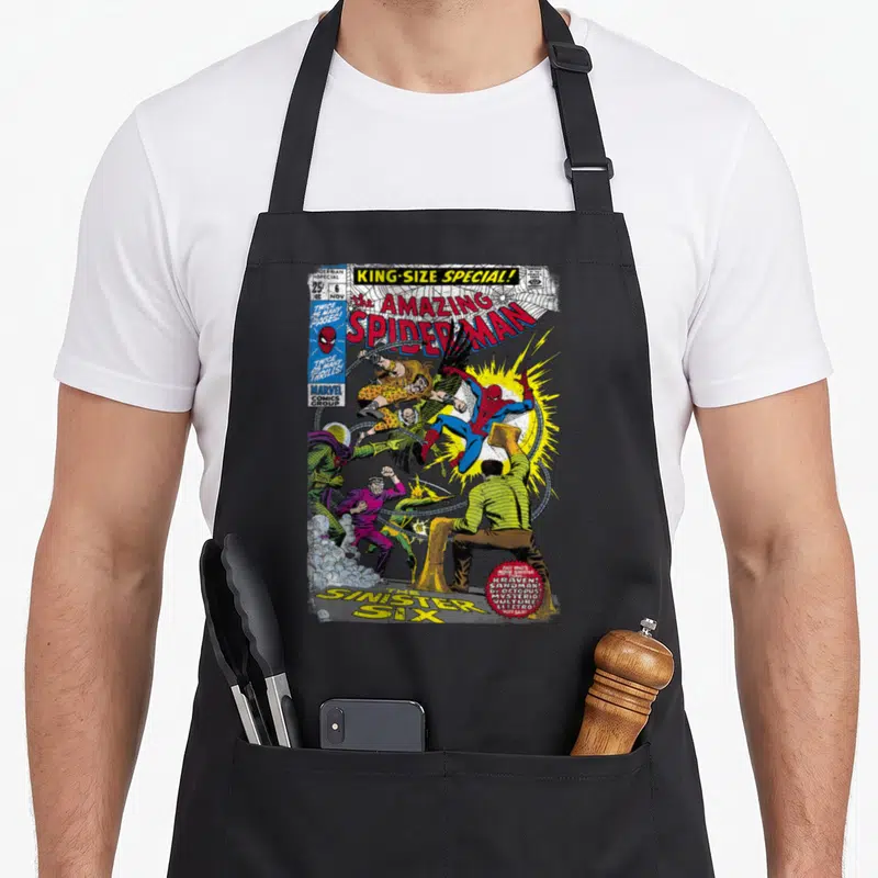 Tablier de cuisine noir avec une illustration colorée de Spider-Man combattant ses ennemis sur fond de bande dessinée américaine.