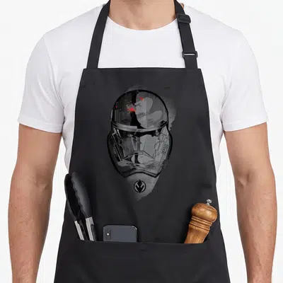Tablier de cuisine noir avec illustration stylisée d'un casque de Sith Trooper en noir, blanc et touches de rouge vif.