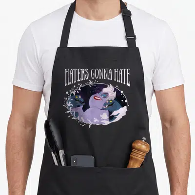 Tablier de cuisine noir avec l'illustration d'Ursula et des crabes sous la phrase Haters Gonna Hate en lettres blanches.