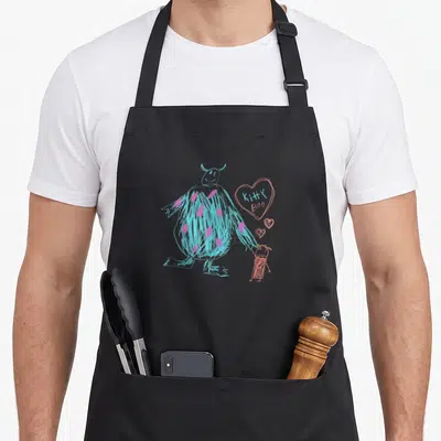 Tablier de cuisine noir avec dessin crayon coloré d'un monstre bleu et d'une petite fille tenant la main près d'un cœur rose.
