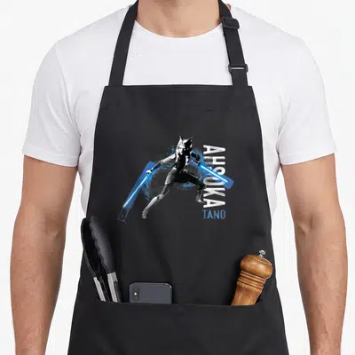 Tablier de cuisine noir avec illustration d'Ahsoka Tano brandissant deux sabres laser bleus et son nom en typographie stylisée.