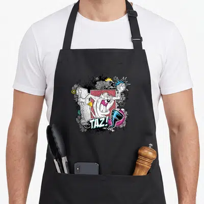 Tablier de cuisine noir avec illustration Taz tenant une porte et le mot TAZ. en lettres stylisées.