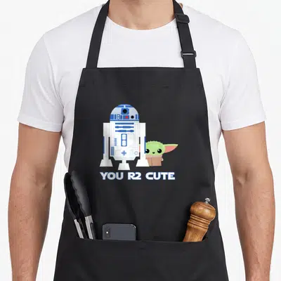 Tablier de cuisine noir avec une illustration de R2-D2, Grogu et le texte You R2 Adorable en bas.