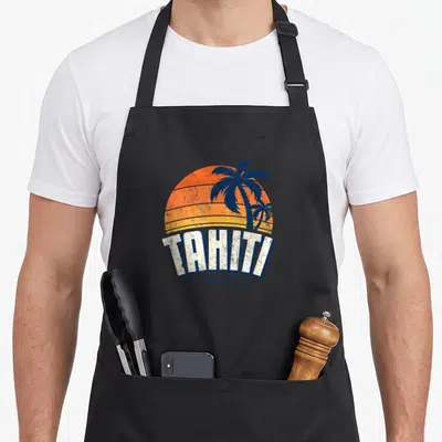 Tablier de cuisine noir avec illustration d'un soleil couchant orange, deux palmiers bleus et le mot Tahiti en lettres blanches capitales.
