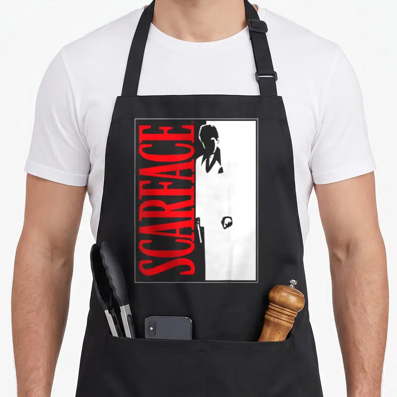 Tablier de cuisine noir avec affiche Scarface rouge et silhouette homme tenant un pistolet.