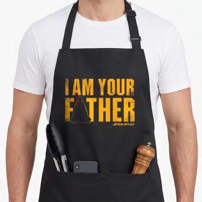 Tablier de cuisine noir avec le texte I AM YOUR FATHER en orange et une silhouette de personnage au sabre laser rouge.