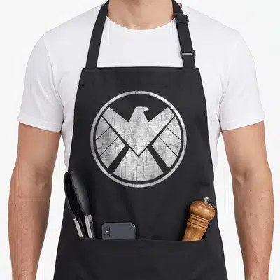 Tablier de cuisine noir avec logo circulaire blanc représentant un aigle au style grunge et effet vieilli.