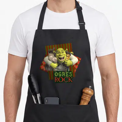 Tablier de cuisine noir avec Shrek, Donkey et Puss en Bottes sous l'inscription Ogres Rock.