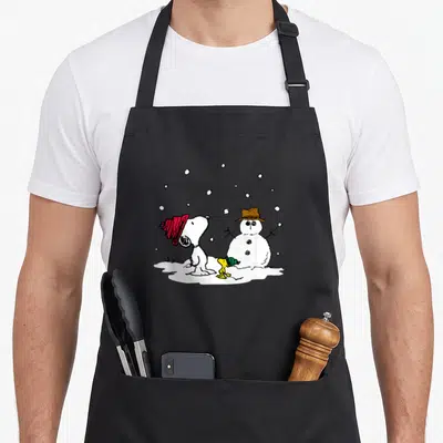 Tablier de cuisine noir avec Snoopy en bonhomme de neige et Woodstock sous la neige