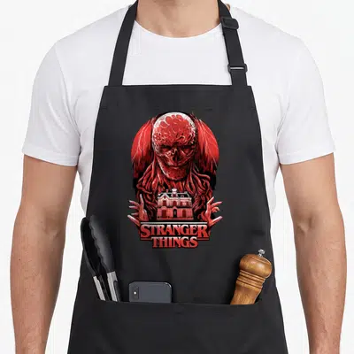 Tablier de cuisine noir avec illustration rouge de Vecna tenant une maison devant des éclairs.