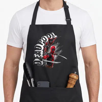 Tablier de cuisine noir avec Deadpool en trois poses d'action brandissant des sabres sous le texte DEADPOOL en blanc.