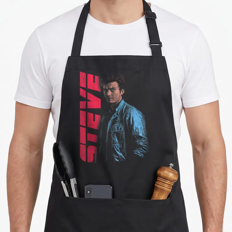 Tablier de cuisine noir avec portrait bleu de Steve et texte rouge vertical.