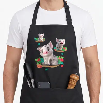 Tablier de cuisine noir avec trois illustrations de Pua le cochon entouré de fleurs tropicales roses et vertes.