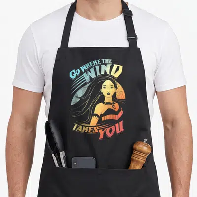 Tablier de cuisine noir avec illustration de Pocahontas et texte Go Where The Wind Takes You en dégradé orange et bleu.