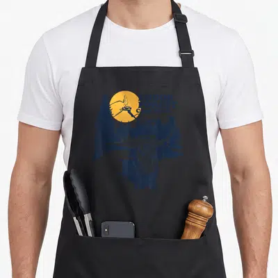 Tablier de cuisine noir avec illustration d'un Ewok tenant une lance sous un soleil orange et des arbres bleus.