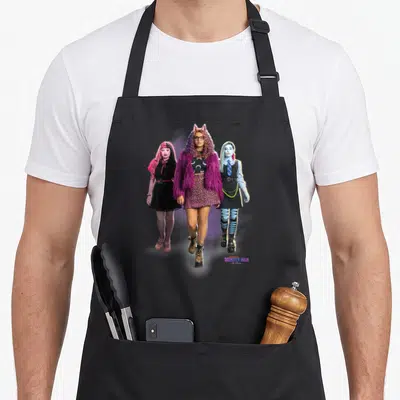 Tablier de cuisine noir avec trois personnages de Monster High en tenues d'étudiantes et le logo du film en bas à droite.
