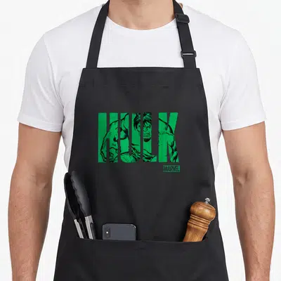 Tablier de cuisine noir avec le mot HULK en vert contenant un dessin de super-héros musclé et le logo Marvel en bas à droite.