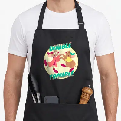 Tablier de cuisine noir avec illustration des souris Jaq et Gus et le texte Double Trouble en lettres turquoise.
