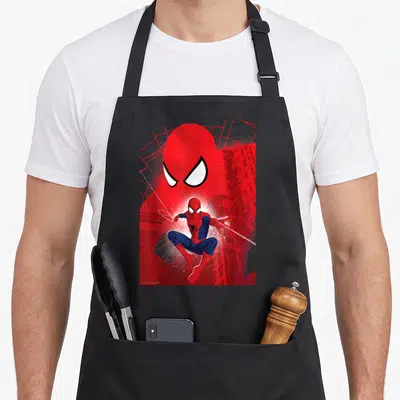 Tablier de cuisine noir avec illustration rouge et bleue de Spider-Man en saut et grands yeux blancs en arrière-plan.