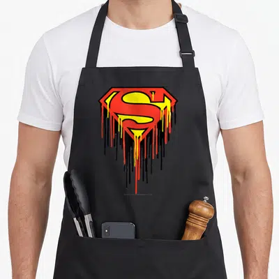 Tablier de cuisine noir avec le logo Superman Drip aux couleurs vives qui dégoulinent vers le bas.
