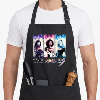 Tablier de cuisine noir avec Miss Marvel, Photon et Captain Marvel en trois panneaux verticaux colorés.
