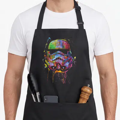 Tablier de cuisine noir avec un casque Stormtrooper multicolore en style éclaboussures de peinture.