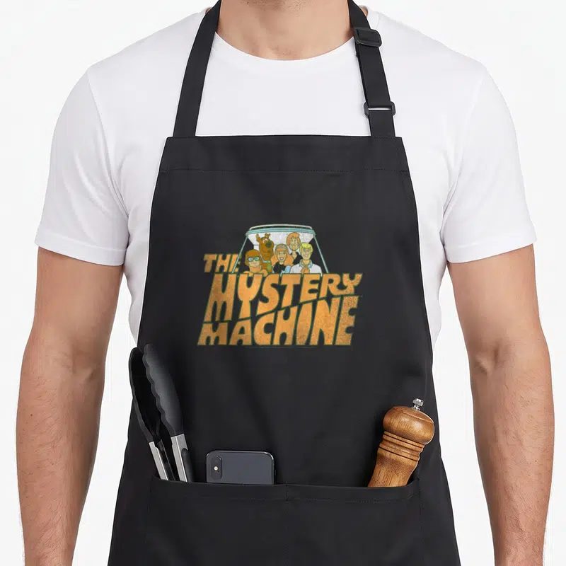 Tablier de cuisine noir avec le logo The Mystery Machine et les personnages du dessin animé en style vintage orange.
