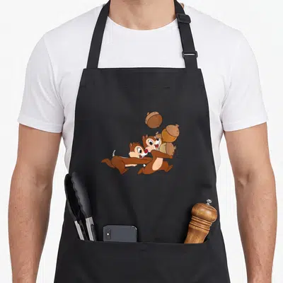 Tablier de cuisine noir avec Chip et Dale courant avec des noix imprimés au centre.