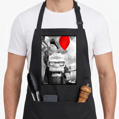 Tablier de cuisine noir avec Carl Fredricksen tenant un ballon rouge et Russell jouant du cor en arrière-plan.