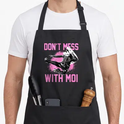 Tablier de cuisine noir avec Miss Piggy effectuant un coup de pied et le texte Don't Mess With Moi en rose vif.