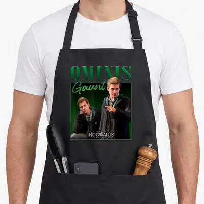 Tablier de cuisine noir avec illustration d'Ominis Gaunt et texte vert Hogwarts Legacy