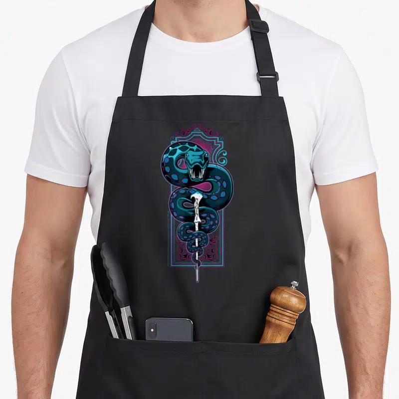 Tablier de cuisine noir avec une illustration colorée de Nagini et d'une baguette portant l'inscription SNAKE.