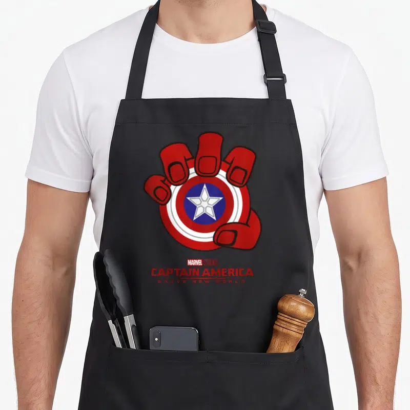 Tablier de cuisine noir avec une main rouge tenant un bouclier Captain America et le texte Brave New World imprimé en dessous.