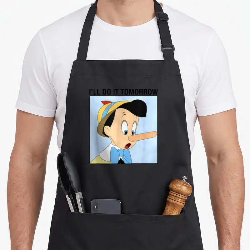Tablier de cuisine noir avec illustration de Pinocchio et texte I'll Do It Tomorrow en haut.