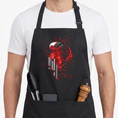 Tablier de cuisine noir avec illustration rouge du personnage Carnage s'enchevêtrant autour d'immeubles gris et le mot Carnage en bas à droite.