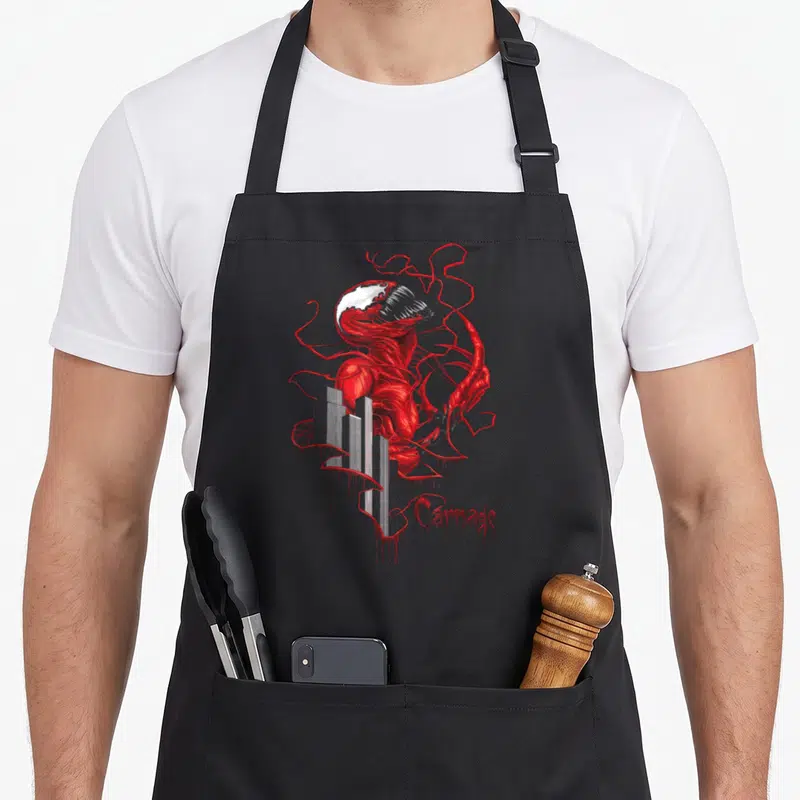 Tablier de cuisine noir avec illustration rouge du personnage Carnage s'enchevêtrant autour d'immeubles gris et le mot Carnage en bas à droite.