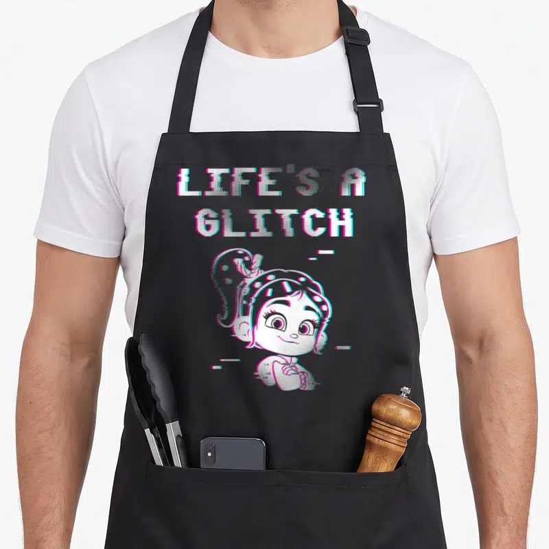 Tablier de cuisine noir avec l'illustration de Vanellope et le texte Life's A Glitch en style pixelisé coloré.
