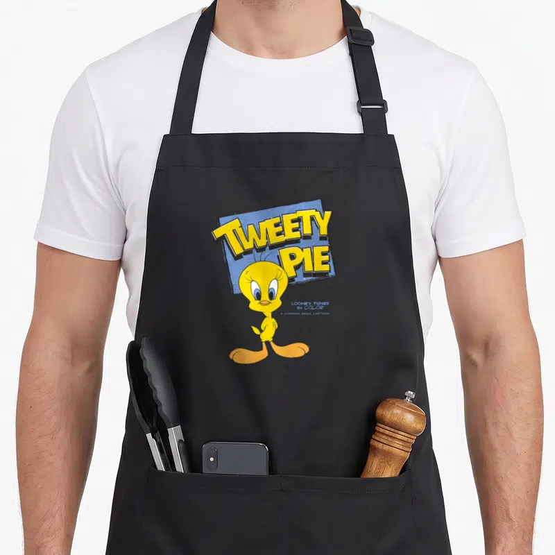 Tablier de cuisine noir avec l'illustration colorée de Tweety Pie et le titre Tweety Pie en lettres jaunes sur fond bleu.