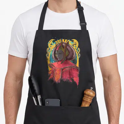 Tablier de cuisine noir avec portrait artistique de Padmé Amidala en tenue royale rouge et coiffure caractéristique encadrée de motifs dorés.