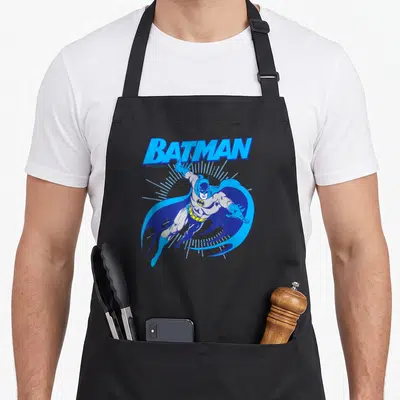 Tablier de cuisine noir avec illustration de Batman en saut et le mot BATMAN en lettres bleues stylisées.