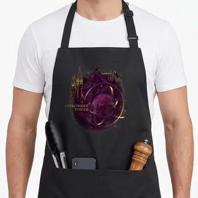Tablier de cuisine noir avec illustration violette et dorée de la tour d'astronomie d'Hogwarts et un globe céleste.
