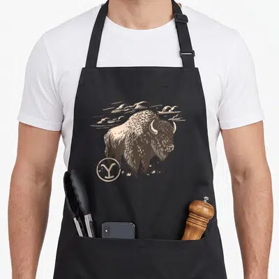 Tablier de cuisine noir avec illustration bison Yellowstone Wild Bison et logo Y circulaire en beige et brun.