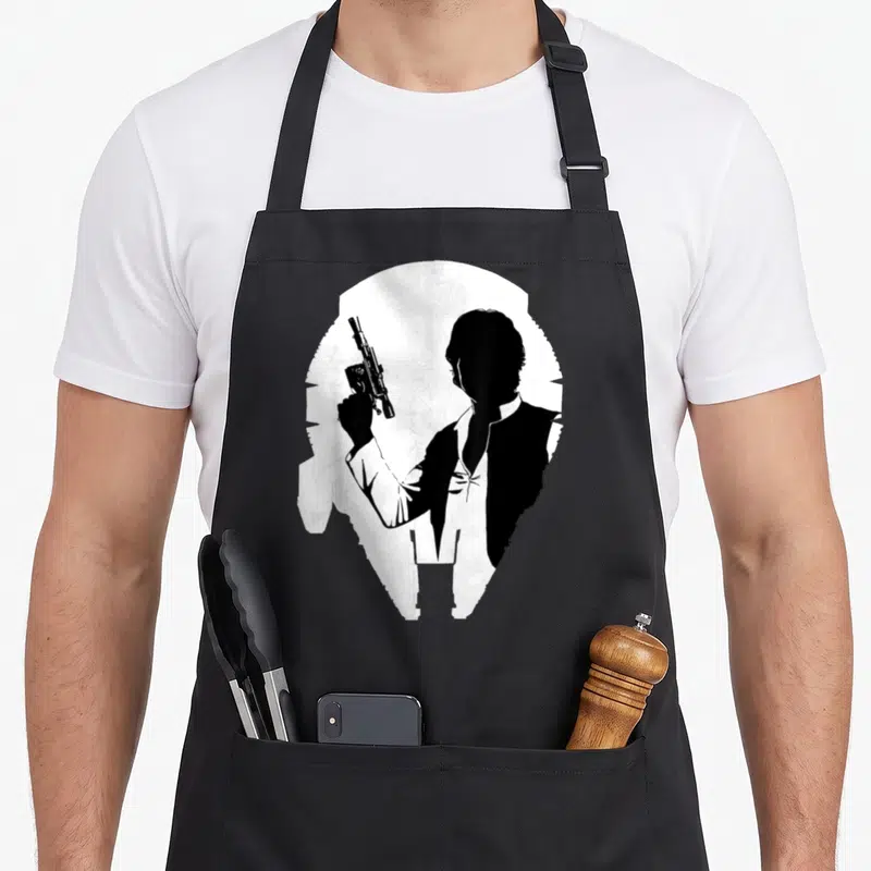 Tablier de cuisine noir avec silhouette Han Solo et schéma Faucon Millénium en blanc.