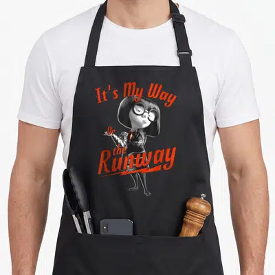 Tablier de cuisine noir avec Edna Mode et le texte It's My Way Or the Runway en orange.