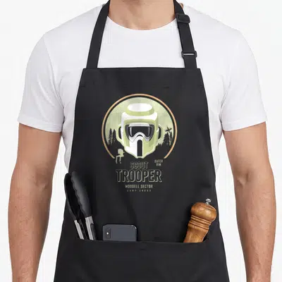 Tablier de cuisine noir avec illustration d'un casque de Scout Trooper et le texte Camp Endor modell sector outer rim.
