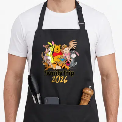 Tablier de cuisine noir avec Winnie l'ourson, Tigger, Piglet et amis sous le texte Family Trip 2026.